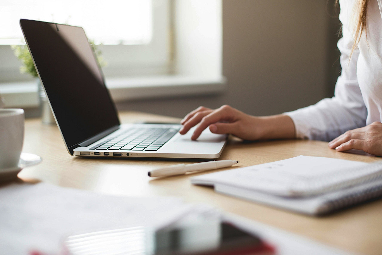 A woman's hands working on a laptop